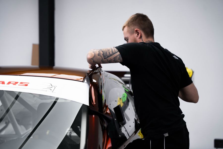 Installer fitting STEK film over a rear quarter