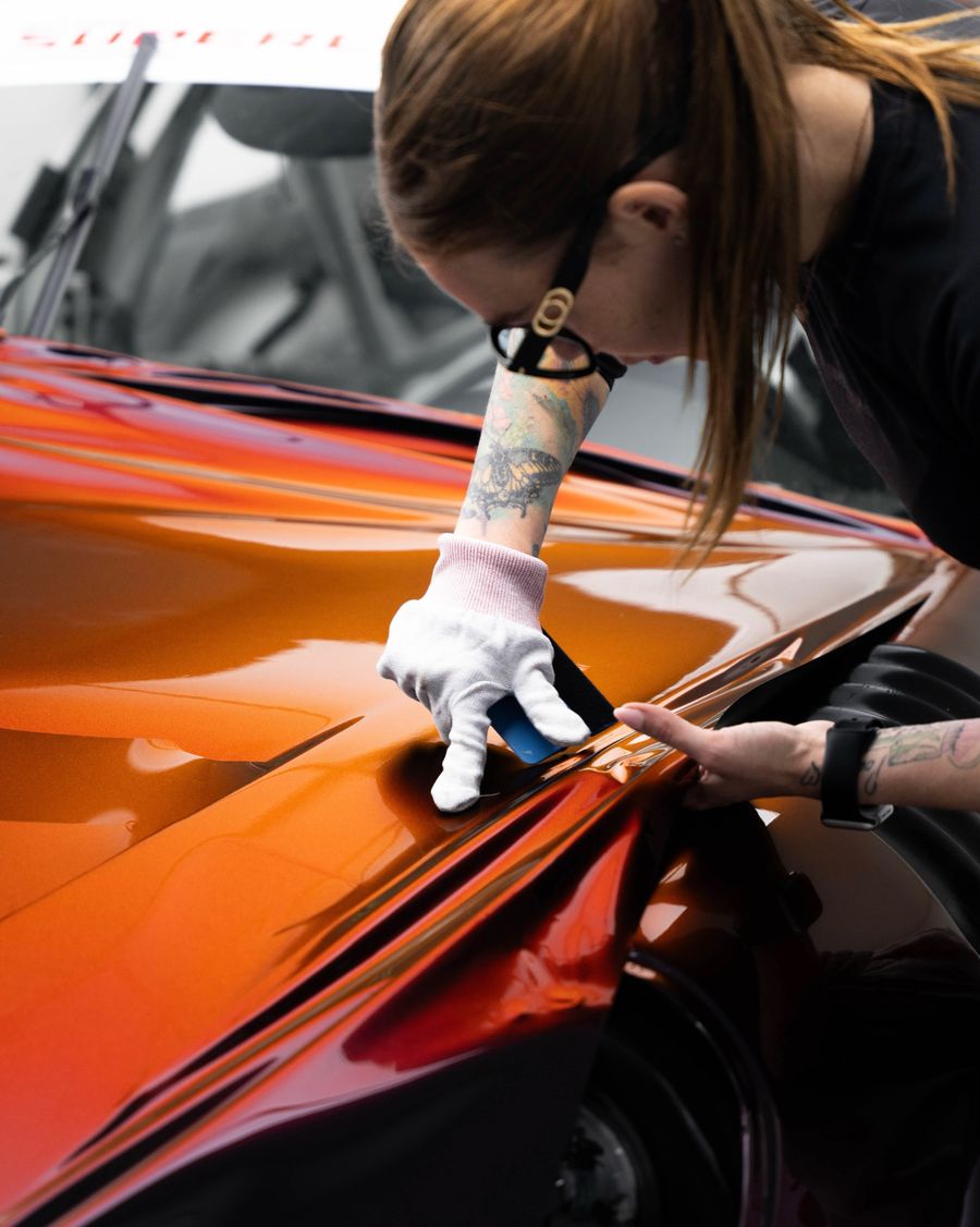 Installer squeegeeing STEK film onto a bonnet